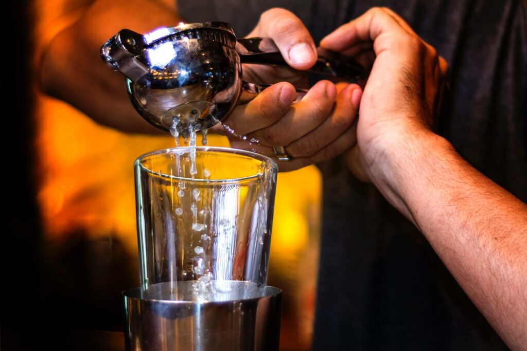 bartender squeezing lemon into cocktail shaker